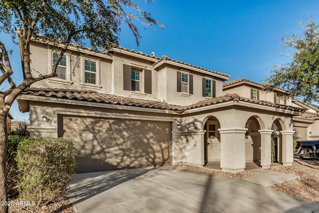 mediterranean / spanish-style home featuring an attached garage, driveway, a tile roof, and stucco siding