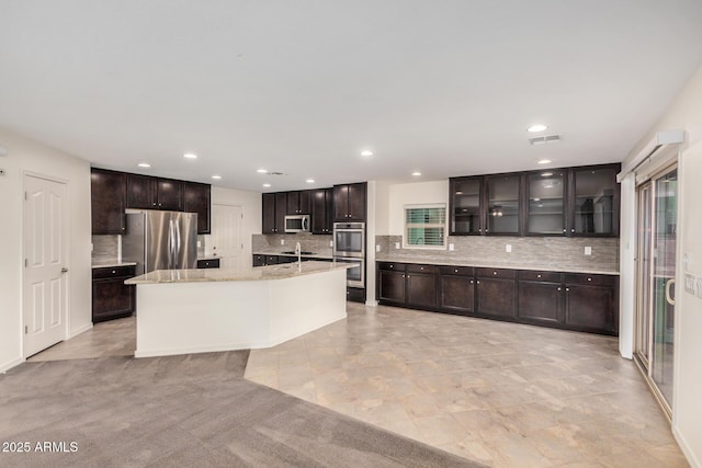 kitchen with recessed lighting, visible vents, appliances with stainless steel finishes, decorative backsplash, and glass insert cabinets