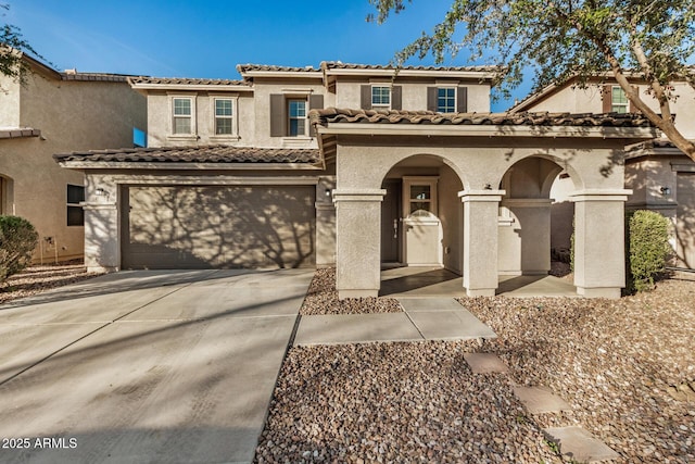 mediterranean / spanish house with a garage, driveway, a tiled roof, and stucco siding