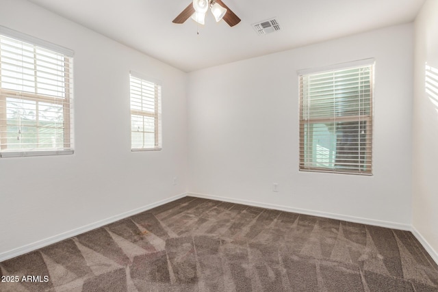 spare room with carpet floors, baseboards, visible vents, and a ceiling fan