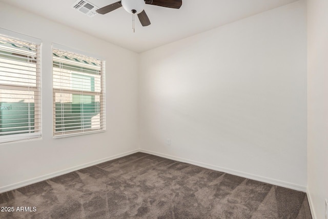 empty room with ceiling fan, dark carpet, visible vents, and baseboards