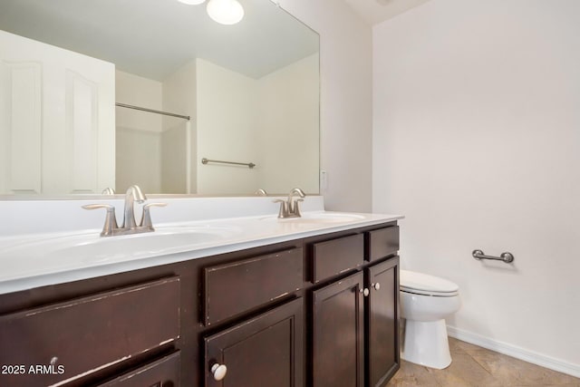 full bathroom with baseboards, a sink, toilet, and double vanity