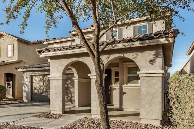 view of front of property with a garage, driveway, a tile roof, and stucco siding