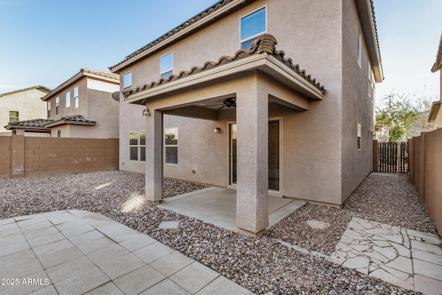 rear view of property featuring a patio area, ceiling fan, a fenced backyard, and stucco siding