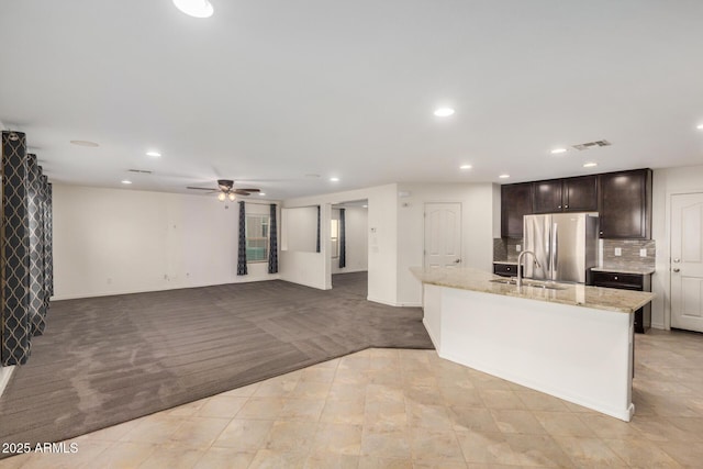 kitchen featuring dark brown cabinetry, recessed lighting, light colored carpet, freestanding refrigerator, and decorative backsplash