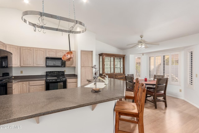 kitchen with sink, light hardwood / wood-style flooring, a kitchen breakfast bar, black appliances, and light brown cabinets