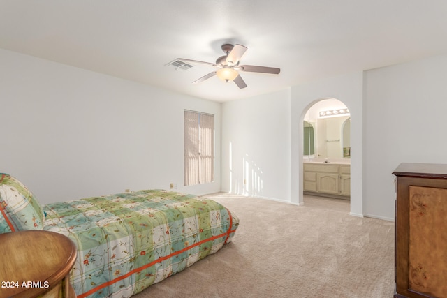 bedroom with light carpet, ensuite bath, and ceiling fan