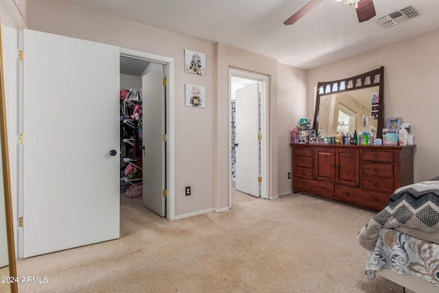 carpeted bedroom featuring ceiling fan, a closet, ensuite bath, and a walk in closet