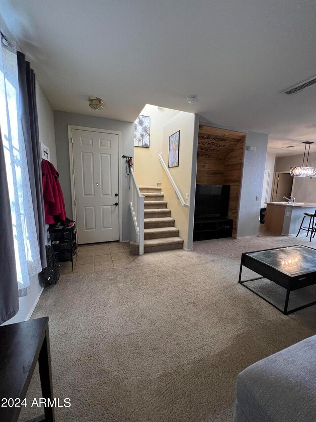 living room featuring light carpet, wood walls, and an inviting chandelier