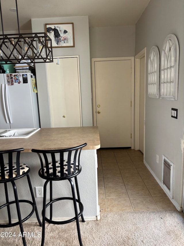 kitchen with a breakfast bar, light tile patterned floors, and white fridge