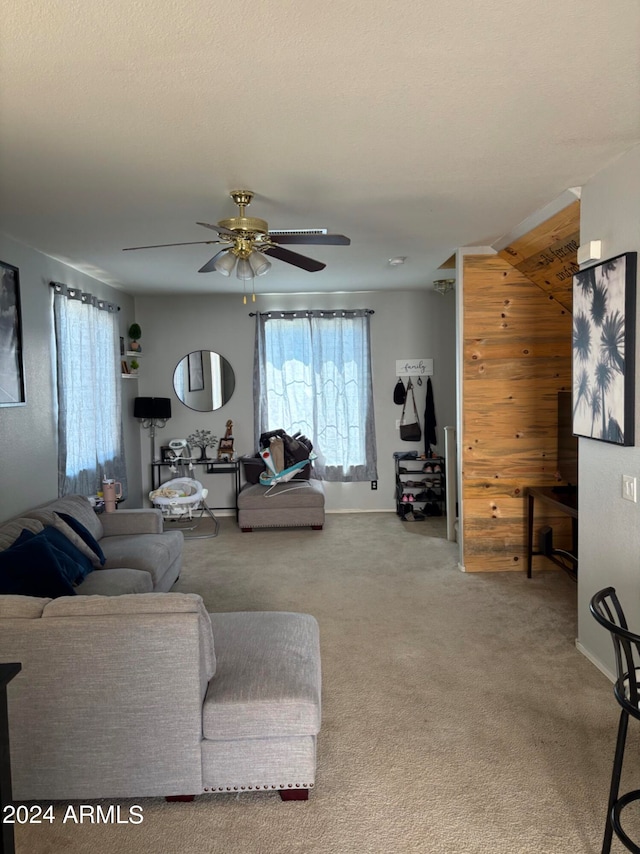 living room featuring ceiling fan, wood walls, and carpet