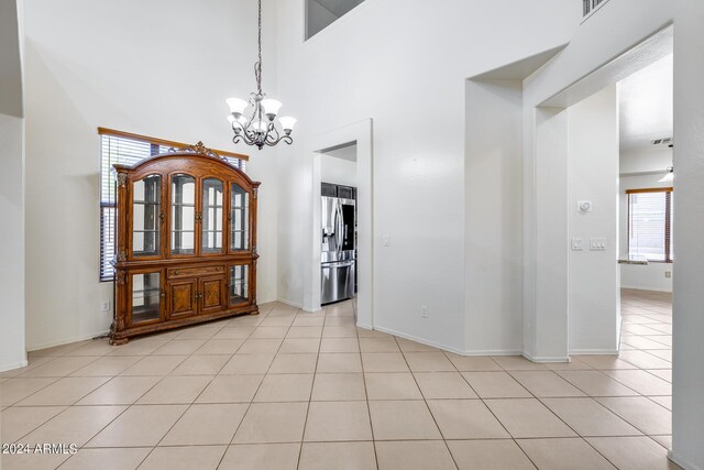 interior space with a high ceiling, light tile patterned floors, and an inviting chandelier