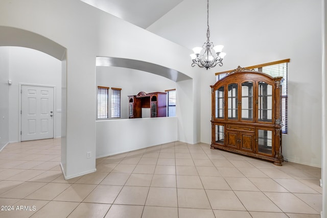 foyer entrance featuring light tile patterned flooring, an inviting chandelier, and a towering ceiling