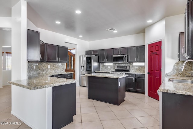 kitchen featuring appliances with stainless steel finishes, tasteful backsplash, light tile patterned floors, sink, and kitchen peninsula