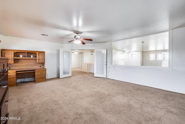 unfurnished living room with light carpet and ceiling fan