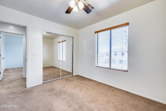 unfurnished bedroom featuring light carpet, a closet, and ceiling fan