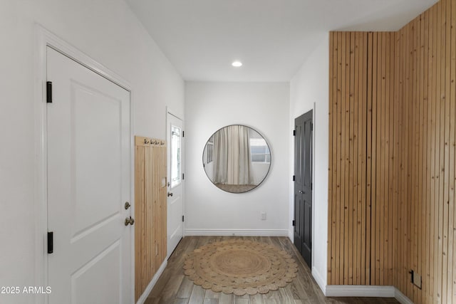 hallway featuring wood walls, baseboards, wood finished floors, and recessed lighting