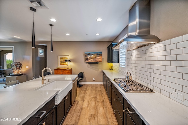 kitchen featuring pendant lighting, decorative backsplash, sink, ventilation hood, and light stone counters