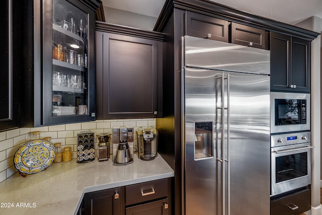 kitchen featuring backsplash, dark brown cabinets, and built in appliances