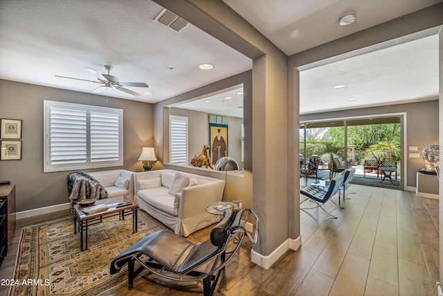 living room featuring ceiling fan and a textured ceiling