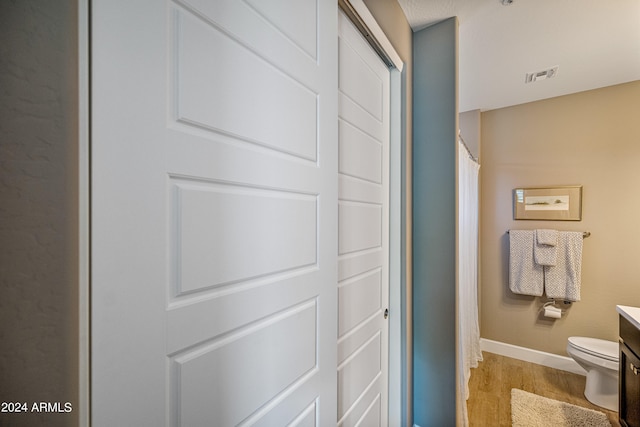 bathroom featuring wood-type flooring, toilet, and vanity