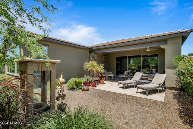 rear view of property featuring ceiling fan and a patio