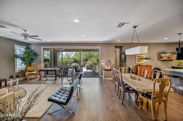 dining area with wood-type flooring, a textured ceiling, and ceiling fan