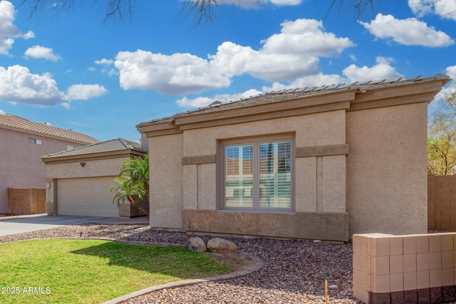 view of front of property featuring driveway, an attached garage, fence, and stucco siding