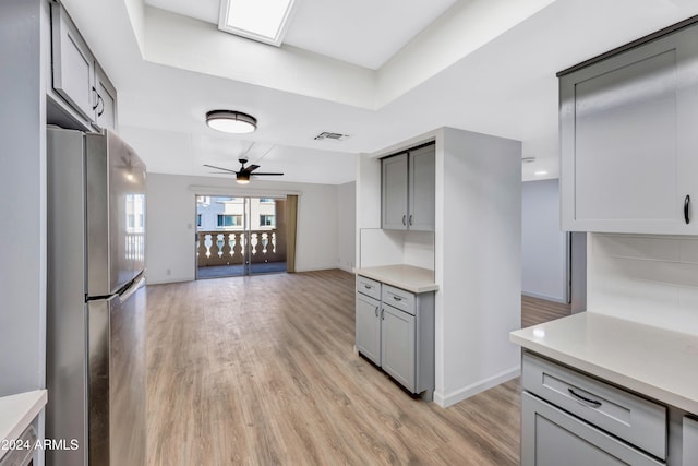 kitchen featuring decorative backsplash, stainless steel fridge, light wood-type flooring, gray cabinets, and ceiling fan