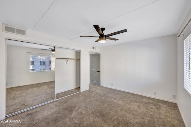 unfurnished bedroom featuring a closet, multiple windows, carpet floors, and ceiling fan