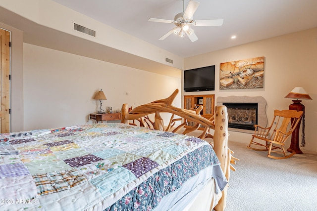 carpeted bedroom featuring ceiling fan, a fireplace, and visible vents