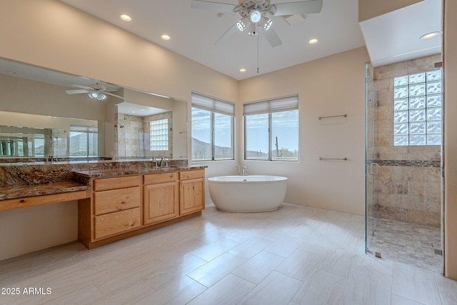 full bath featuring recessed lighting, a freestanding bath, a ceiling fan, a stall shower, and vanity