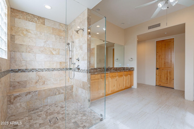 full bathroom featuring ceiling fan, visible vents, tiled shower, and vanity