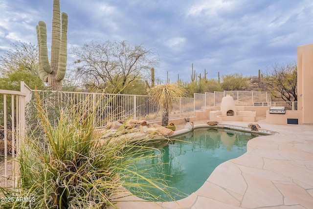 view of swimming pool featuring a patio, area for grilling, fence, exterior kitchen, and a fenced in pool