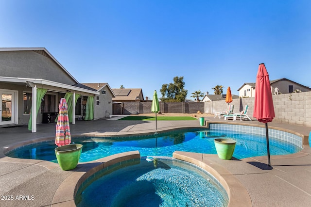 view of pool featuring a patio area, a fenced backyard, and a pool with connected hot tub