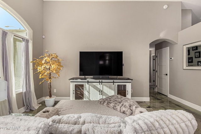 living area featuring arched walkways, marble finish floor, and baseboards