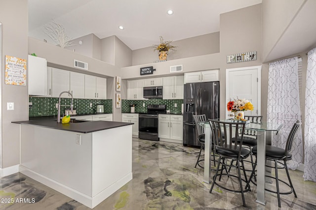 kitchen with stainless steel appliances, dark countertops, a sink, and visible vents