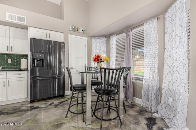 dining area with a towering ceiling, visible vents, and baseboards