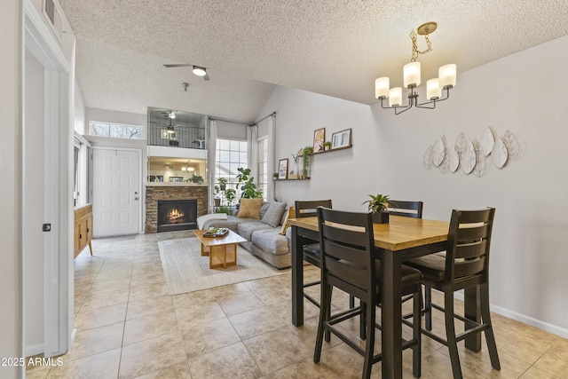 dining space with light tile patterned flooring, vaulted ceiling, a fireplace, a textured ceiling, and an inviting chandelier
