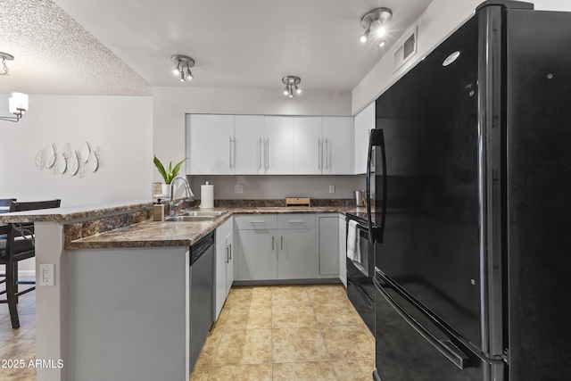 kitchen featuring a sink, white cabinets, a peninsula, light tile patterned floors, and black appliances