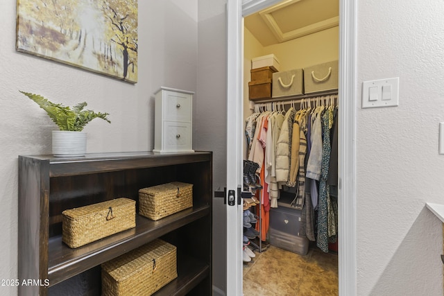 spacious closet featuring tile patterned floors and attic access
