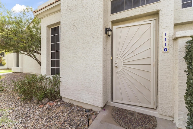 entrance to property featuring stucco siding and a tile roof
