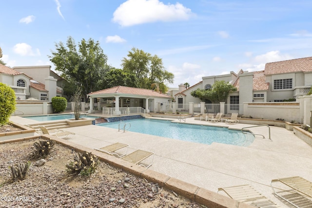 pool with an outdoor structure, an exterior structure, fence, and a patio