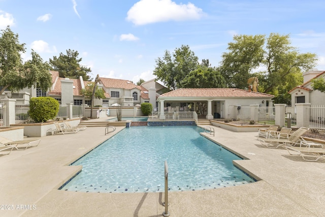 community pool with fence, a residential view, and a patio area