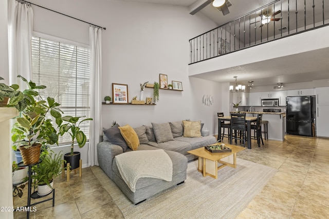 living area featuring light tile patterned flooring, ceiling fan with notable chandelier, and high vaulted ceiling