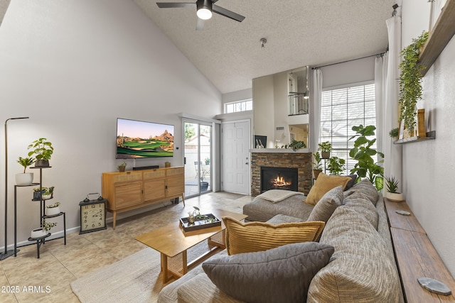 living room with a ceiling fan, a stone fireplace, a healthy amount of sunlight, and a textured ceiling