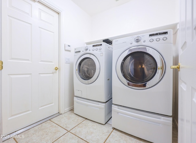 laundry area featuring washing machine and dryer and light tile patterned floors