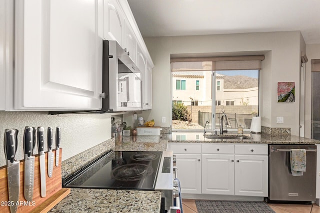 kitchen with light stone counters, appliances with stainless steel finishes, white cabinets, and a sink