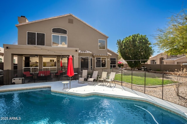 back of property with a fenced in pool, a tile roof, fence, a patio area, and stucco siding