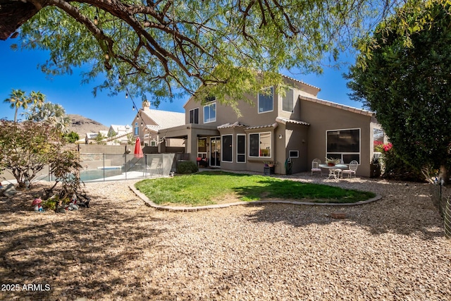 back of property featuring fence, a tiled roof, a lawn, stucco siding, and a patio area